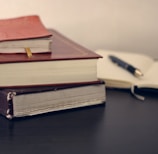 selective focus photography of three books beside opened notebook