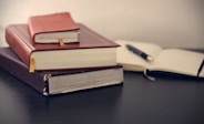 selective focus photography of three books beside opened notebook