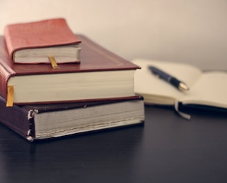 selective focus photography of three books beside opened notebook