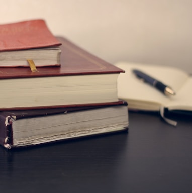 selective focus photography of three books beside opened notebook