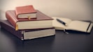 selective focus photography of three books beside opened notebook