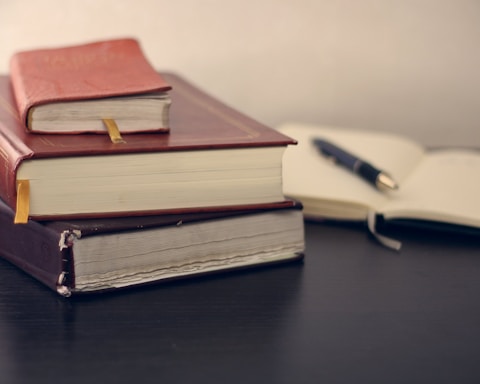 selective focus photography of three books beside opened notebook