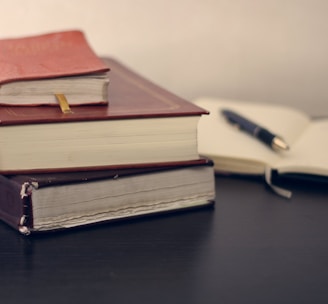 selective focus photography of three books beside opened notebook