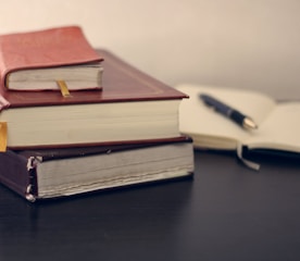 selective focus photography of three books beside opened notebook