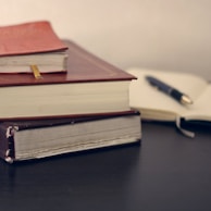 selective focus photography of three books beside opened notebook