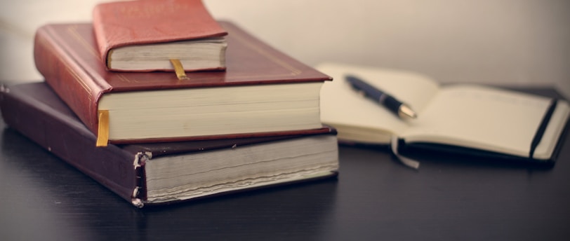 selective focus photography of three books beside opened notebook