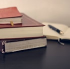 selective focus photography of three books beside opened notebook