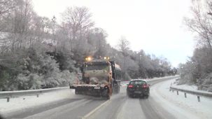 A driveway cleared of snow with a snowplow in action on a winter morning.