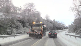Snow-covered driveway being cleared by a professional snow removal service.