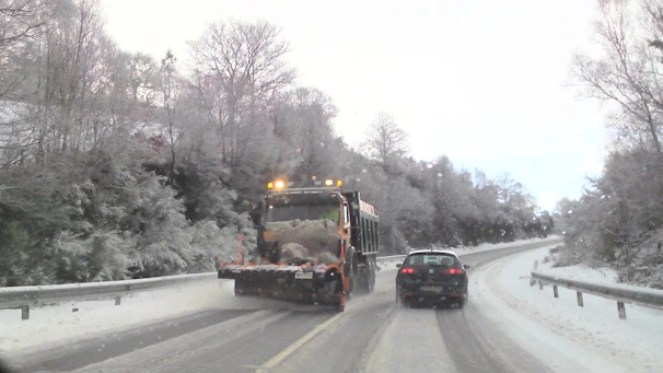 A driveway cleared of snow with a snowplow in action on a winter morning.