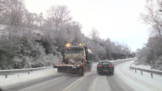A sleek snowplow clearing a driveway in a quiet residential neighborhood at dawn.