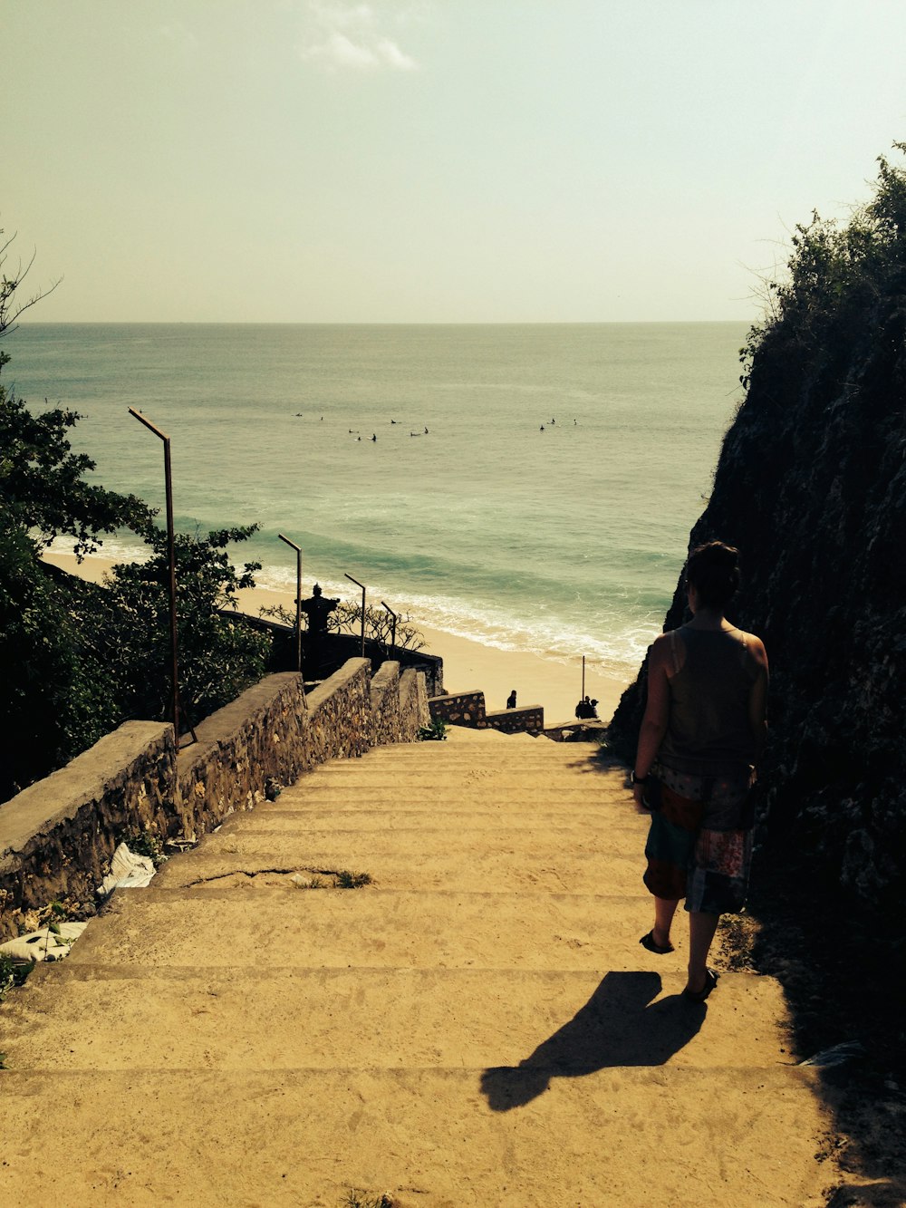 person in gray tank top walking down to shore