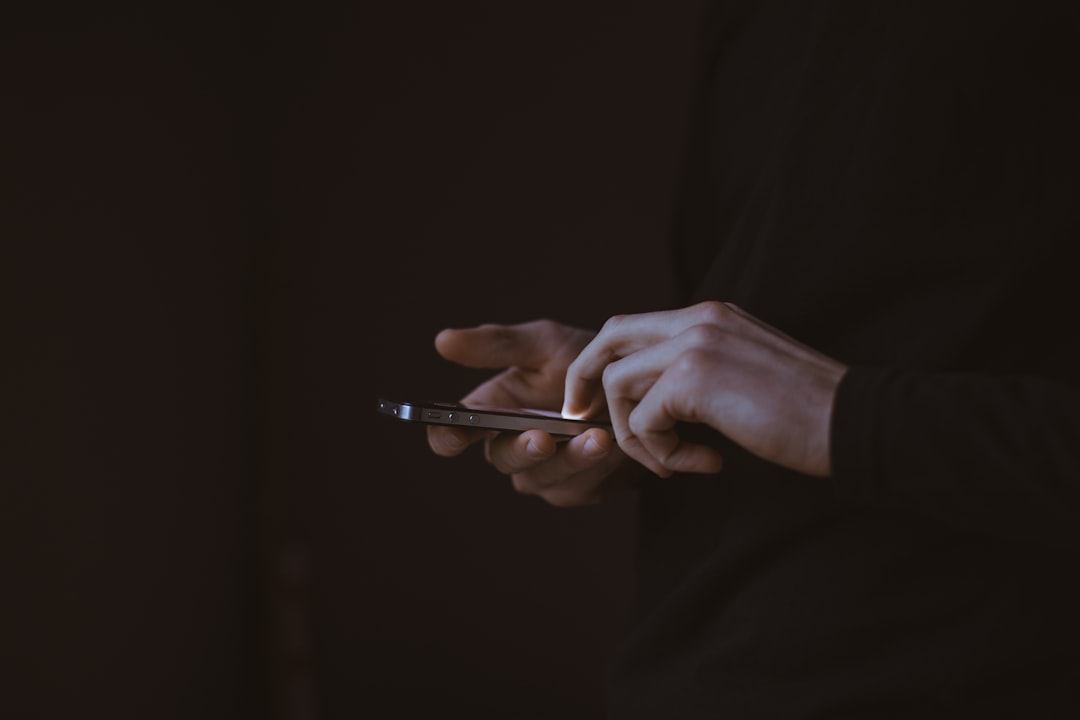 A man in black suit’s hand operating an Apple company gadget- An iphone smartphone