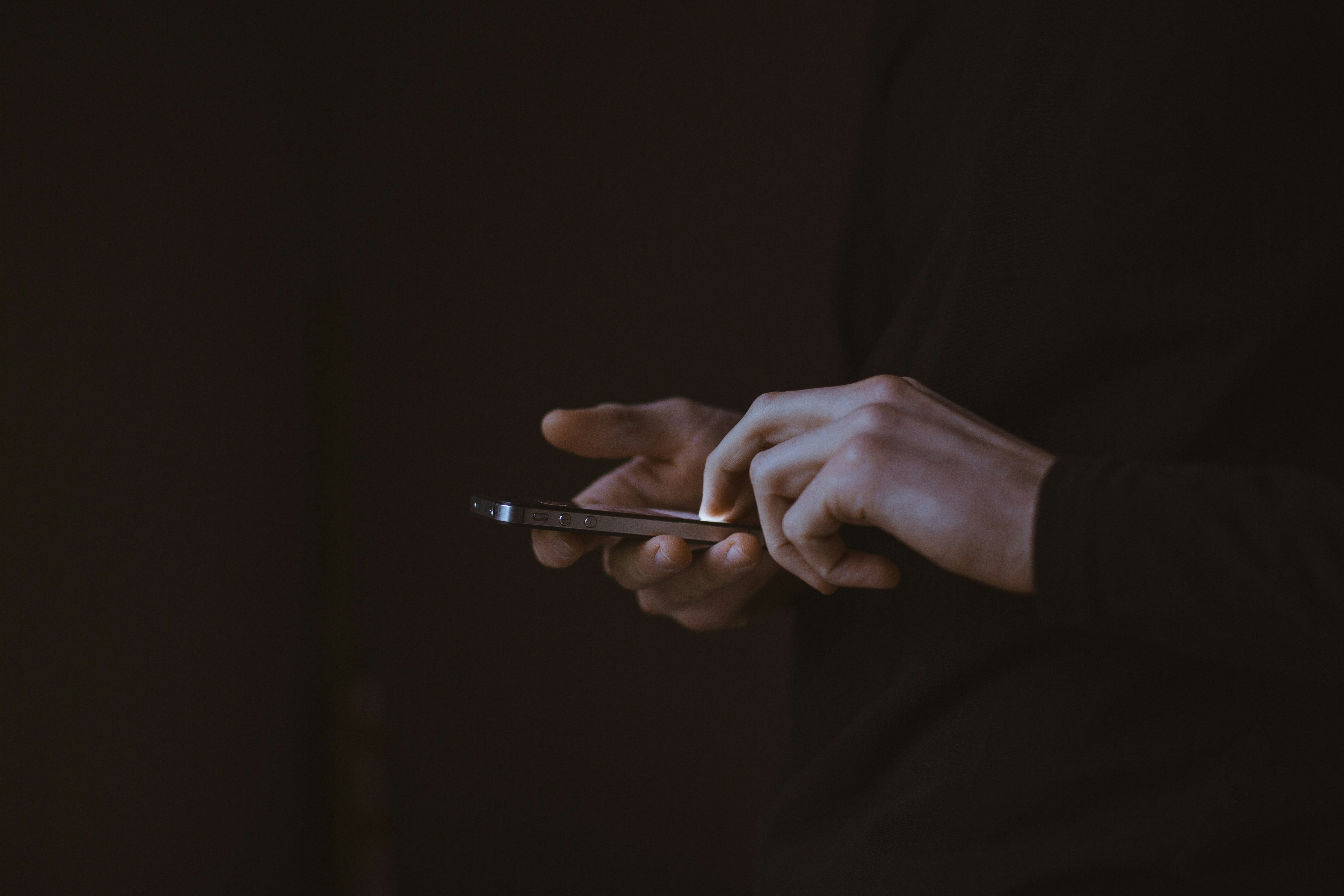 hands operating a modern smartphone showing text messaging interface with custom dark mode theme