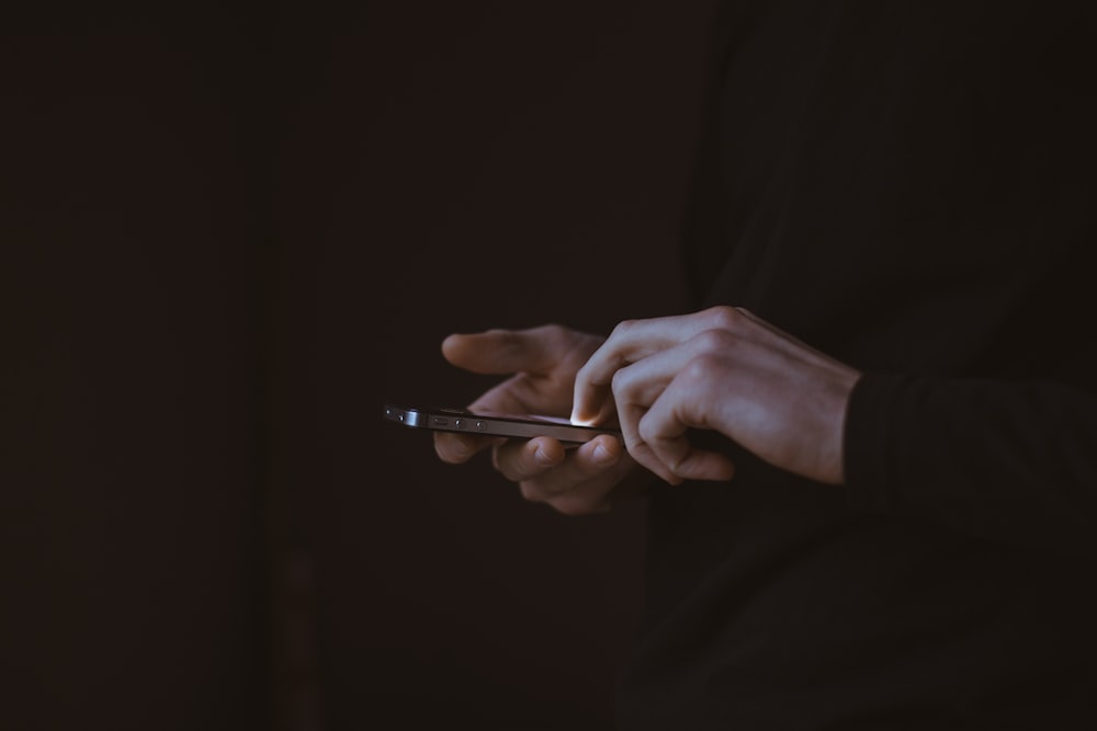 silhouette photo of person holding smartphone