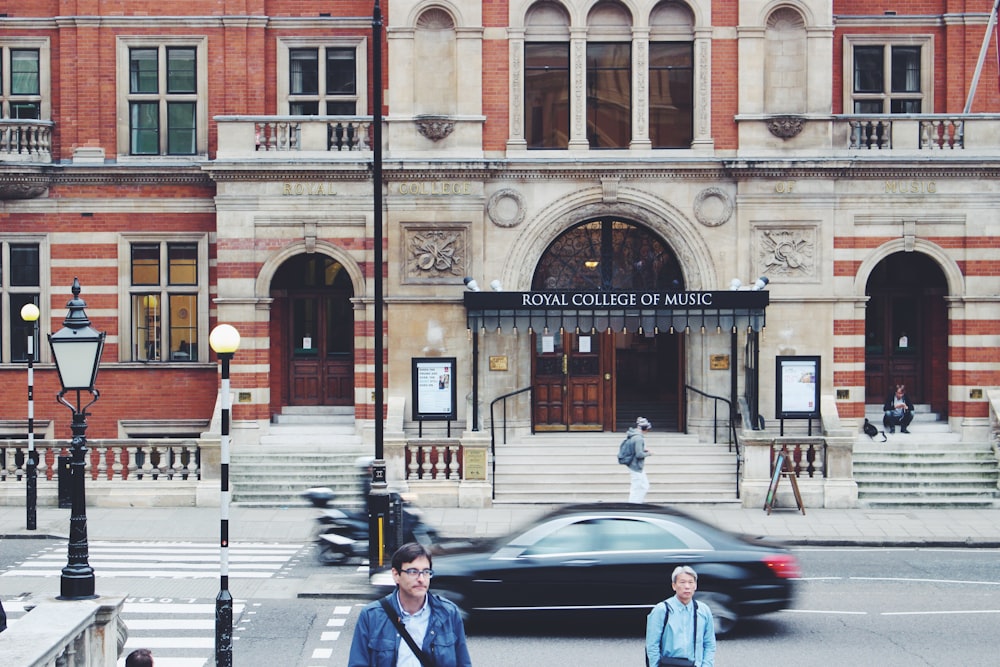 fotografia de foco seletivo do homem caminhando perto do edifício do Royal College of Music