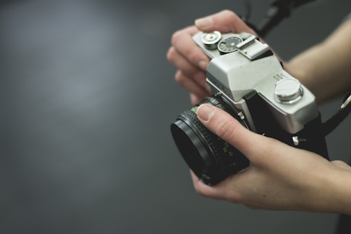 A close-up of hands holding a vintage camera in soft natural light.