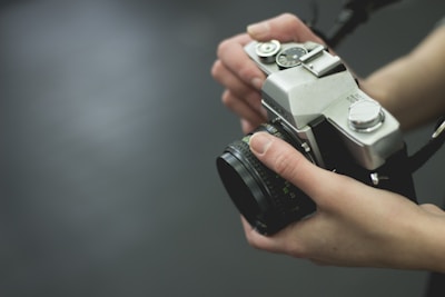 A close-up shot of a photographer’s hands adjusting a vintage camera, symbolizing care and attention to detail.