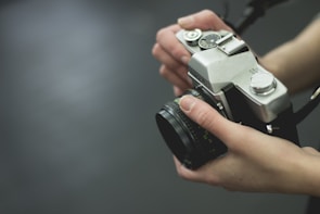 Close-up of hands gently holding a vintage camera on a minimalist background.