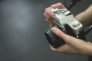 A detailed shot of hands holding a vintage camera in soft focus.