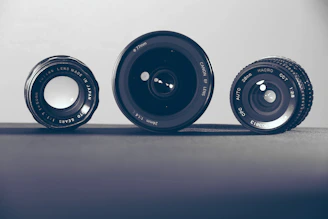 three black camera lenses on gray surface