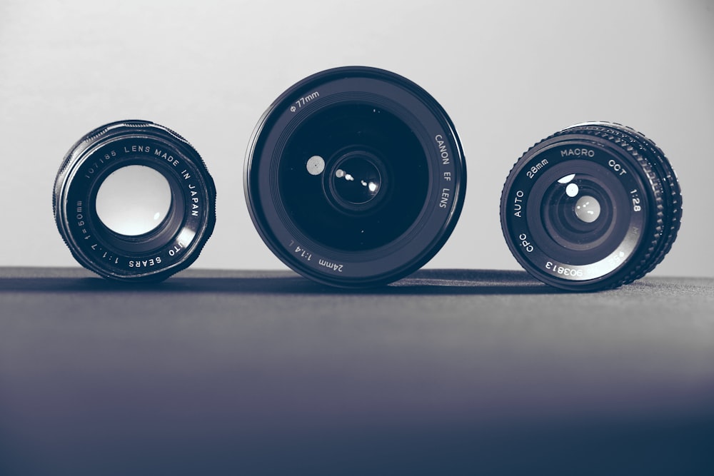three black camera lenses on gray surface