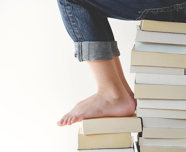 person sitting on stack of books while reading