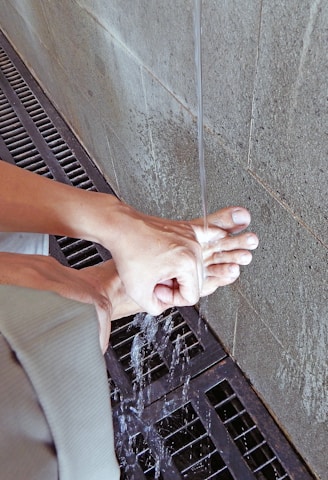 Hands carefully scrubbing grout between ceramic tiles on a floor.