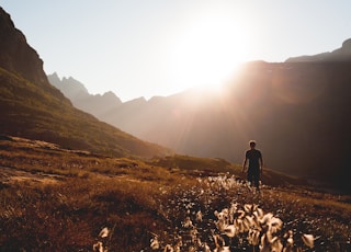 man walking beside the foot of the mountain during daytime