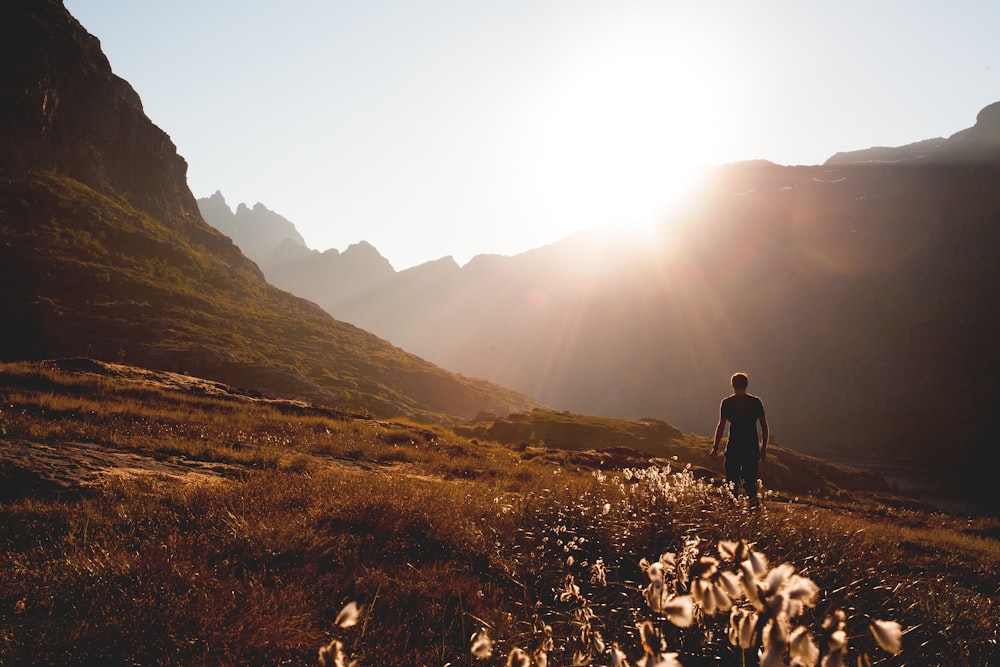 uomo che cammina accanto al piede della montagna durante il giorno