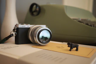 A vintage film camera surrounded by anime figurines and photography gear on a wooden desk.