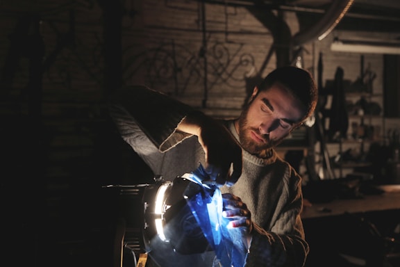 A focused technician adjusting stage lights amidst a dimly lit theatre.