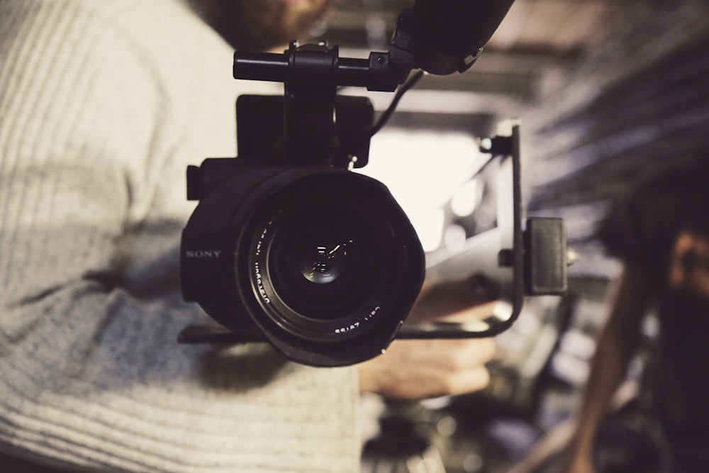 Foto de primer plano de la persona que lleva una grabadora de video profesional