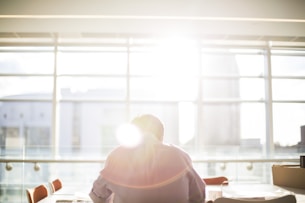 man sitting on chair in front on window during daytime
