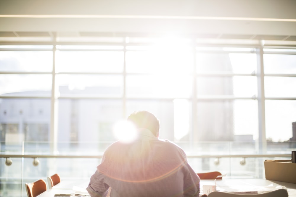 man sitting on chair in front on window during daytime