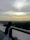 Circular photo of a thoughtful man looking out over a city skyline at sunset.
