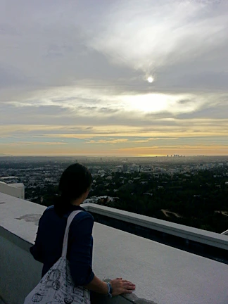 A quiet moment of reflection by a person looking out over a sunset-lit cityscape.