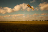 A sleek windsock frame standing sturdy on a grassy airfield at dawn.