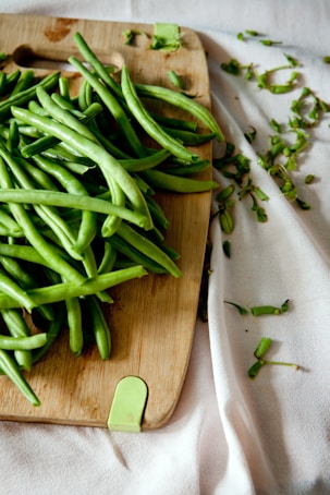 green peas on top of brown wooden chopping board