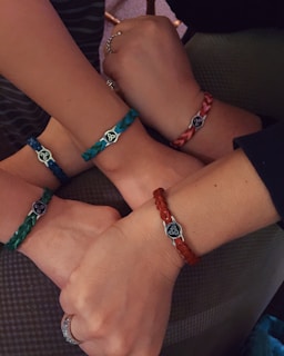 Hands wearing different styles of bracelets in natural light