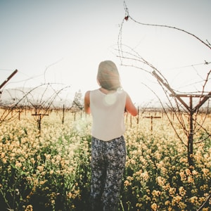 woman standing on ground and surrounded by flowers