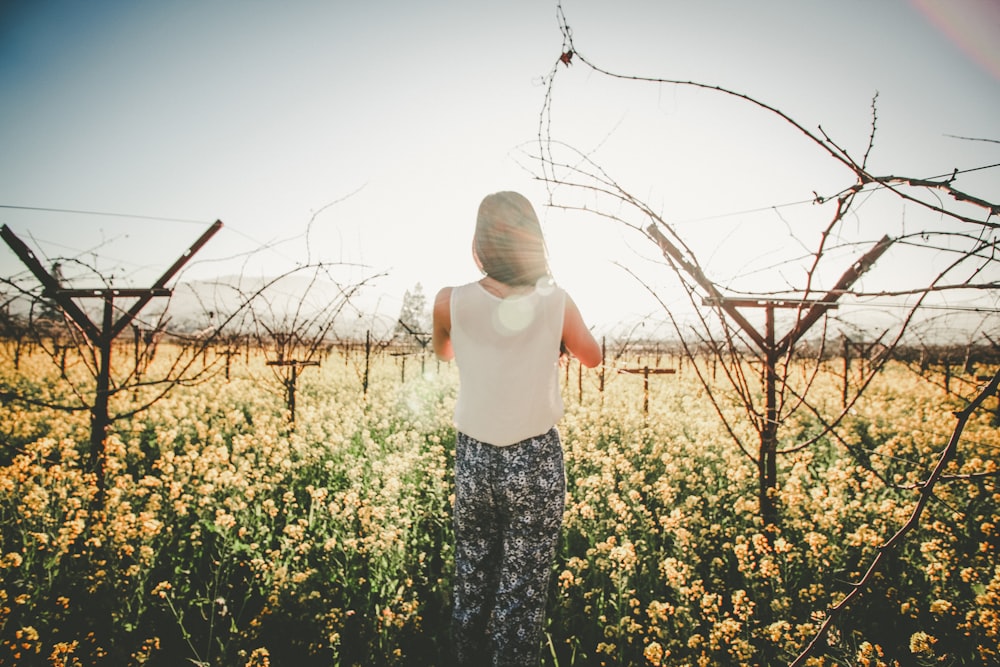 woman standing on ground and surrounded by flowers
