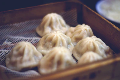 Close-up of freshly steamed dumplings arranged on a traditional bamboo tray, steam gently rising.