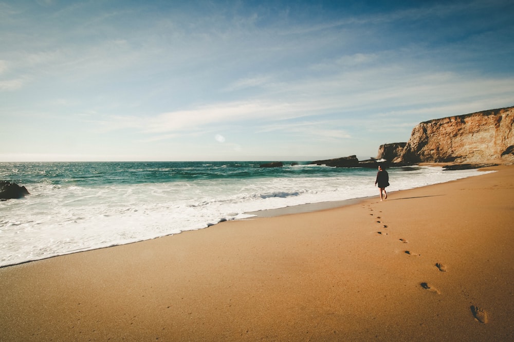 person walking on seashore