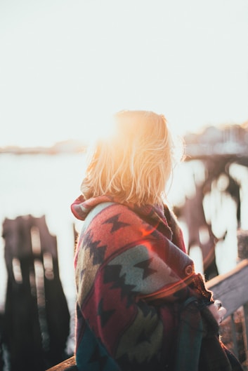 woman covered by multicolored aztec blanket