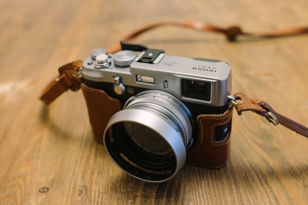 black and silver dslr camera on brown wooden table