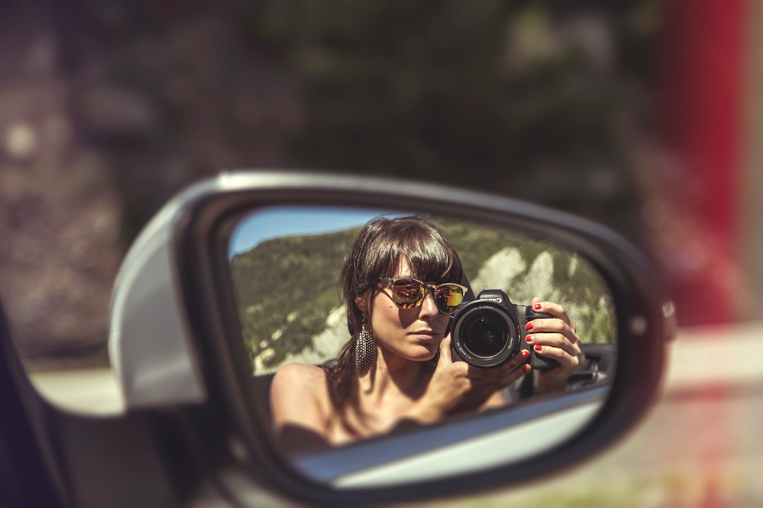 woman in black tank top holding black dslr camera,