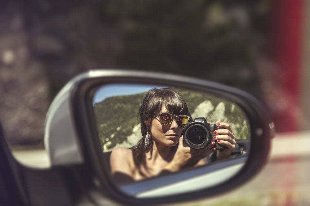 woman in black tank top holding black dslr camera