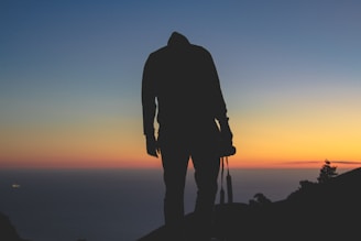 A silhouette of a videographer capturing a sunset.