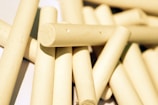 Several pieces of beige cylindrical chalk are scattered in a pile on a light surface, casting subtle shadows.